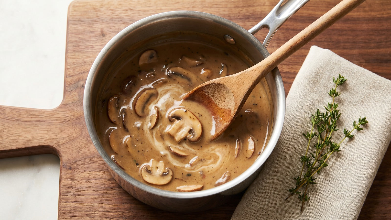 Creamy mushroom sauce in a small saucepan with wooden spoon