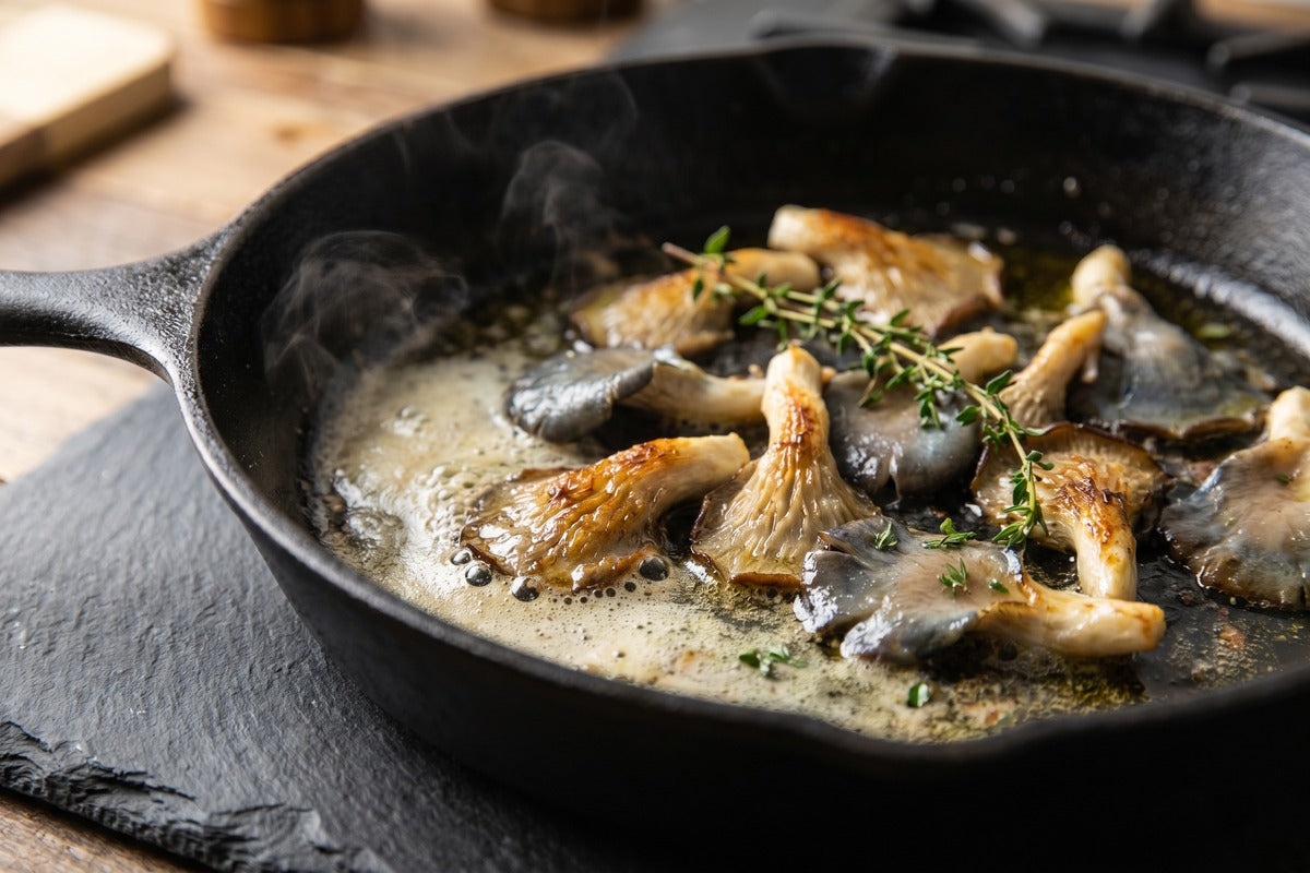Pan-seared blue oyster mushrooms in cast iron skillet with fresh thyme, ready to plate